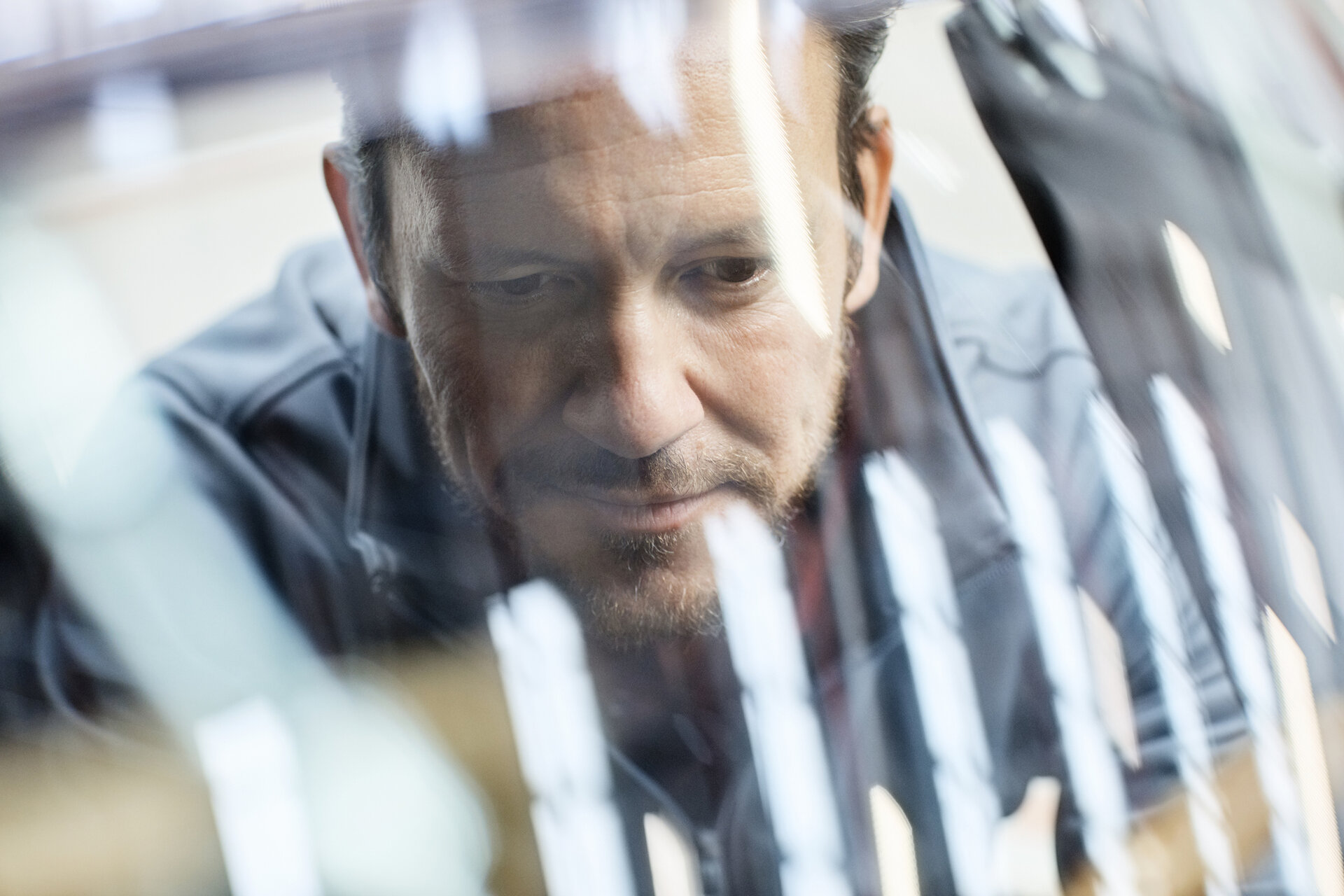 © iStock-916868472_Morsa Images (Close-up of male engineer seen through car windshield. Confident male is repairing vintage vehicle in automobile industry. Technologist is smiling while working in showroom.)